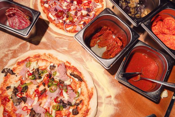 Image of a pizza being made surrounded by ingredients