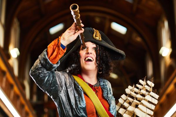 A pirate looking up through her telescope with a smiling face.