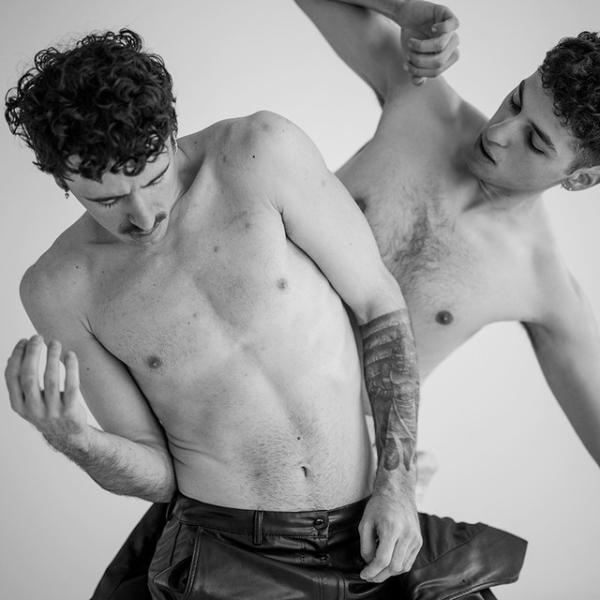 Two male dancers are caught in an intertwined movement