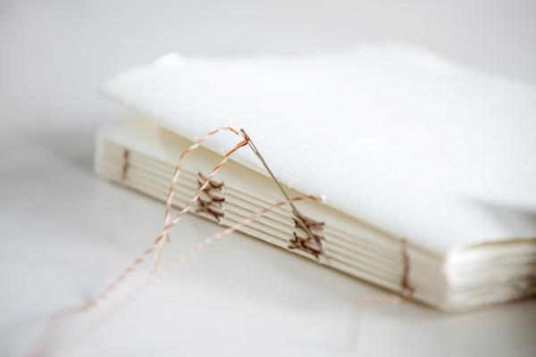 Folded paper with needled and thread.
