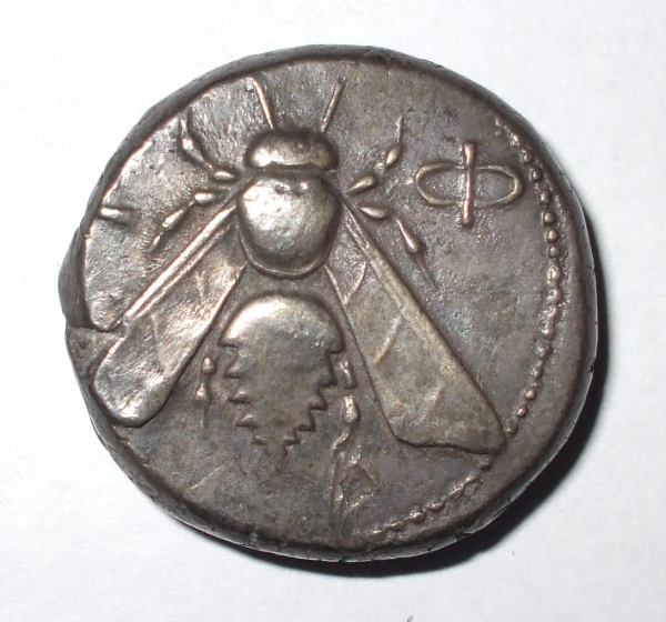 Small silver coin with a bee on the surface.
