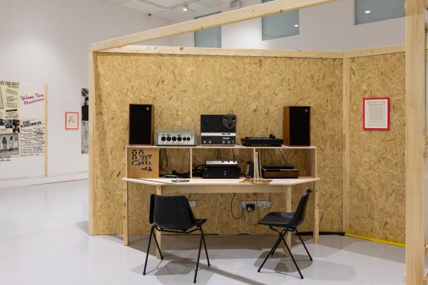 Analogue sound equipment against a wall constructed of chipboard within a white gallery space