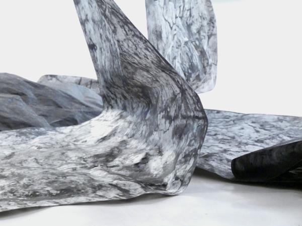 A roll of charcoal covered paper drapes onto the floor