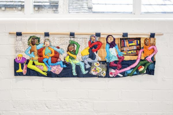 Atiyya's fabric portraits of family and friend hung from a dowel rod on a magnolia painted wall.