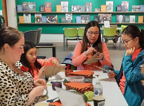 A group of people around a table creating something crafty