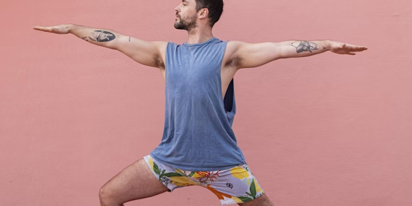Yoga teacher Iain in Warrior 2 pose with his front knee bent and his arms outstretched wide