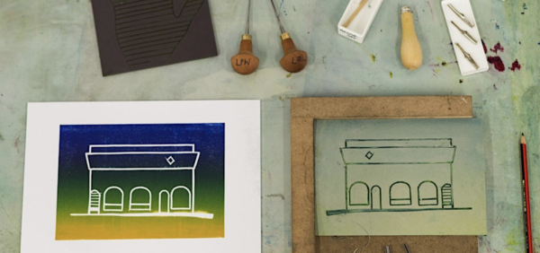 A lino cut and print depicting a building in blues, greens and yellows, alongside a selection of lino cutting tools