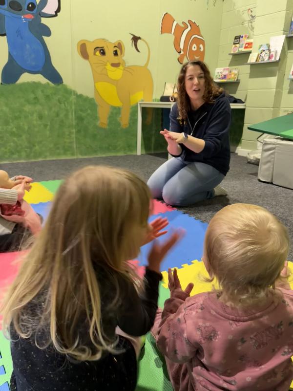 Two young children sitting in front of a storyteller participating in interactive storytelling