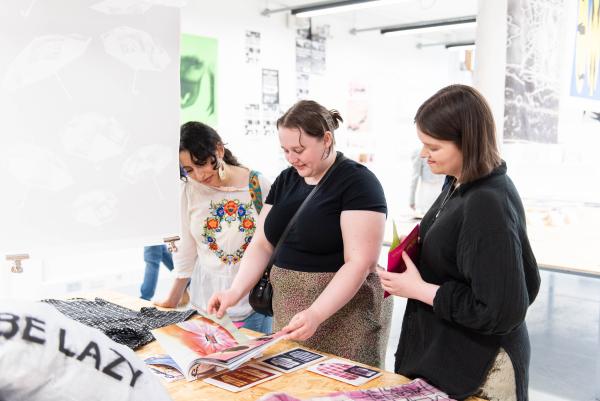 People looking at printed books made by students in a studio