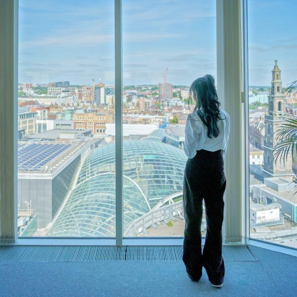 Woman looking out of a window overlooking the city
