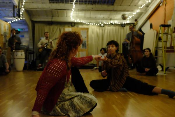Two dancers connecting in front of a range of musicians.
