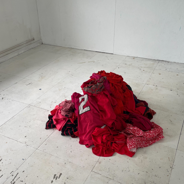 A pile of red clothes sits on a white floor
