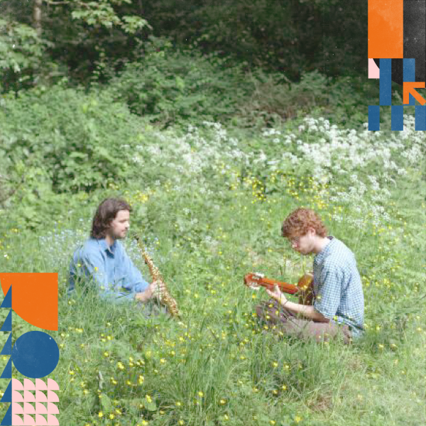Two performers sitting in a field of grass playing music