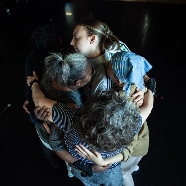 dancers and participants hug one another in a group in the dance studio