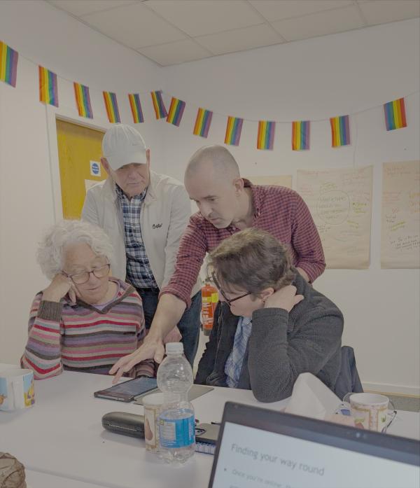 four people gathered around a tablet co-working at Pride Place