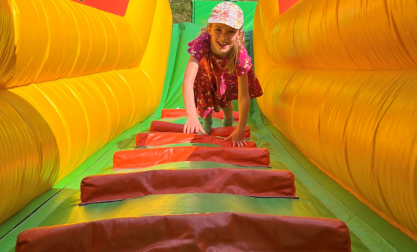 teenage girl climbing up a yellow, green and red inflatable slide