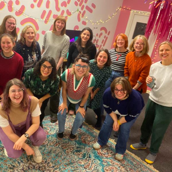 Cosy Choir members smiling at the camera in a colourful room