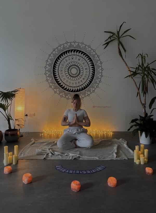 Yoga teacher Olivia sitting crossed legged with her hands in prayer pose