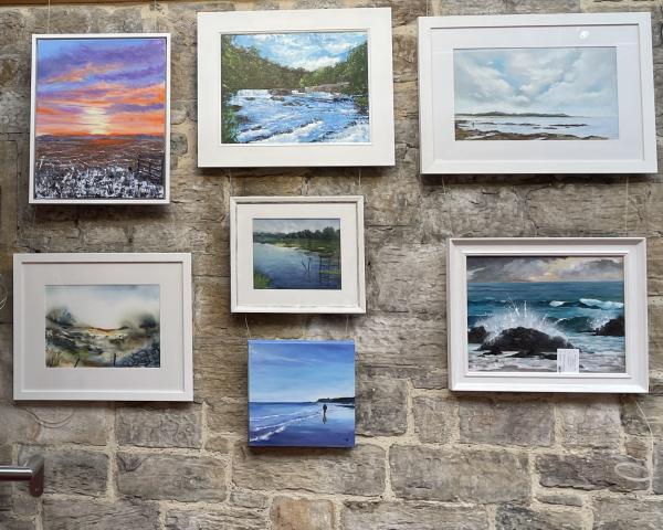 Wall showing landscape and seascape paintings by Jackey Brown