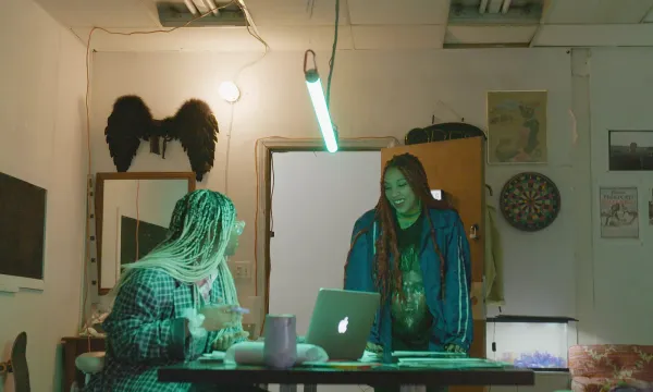 Two people talking over a laptop