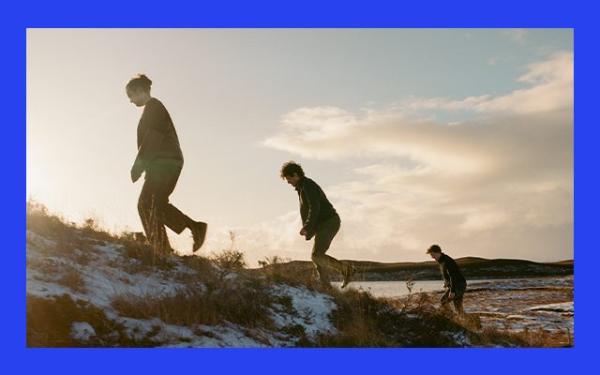 Three men walking up a snowy moorland hill