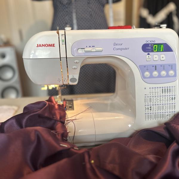 A sewing machine with some burgundy fabric being run through it
