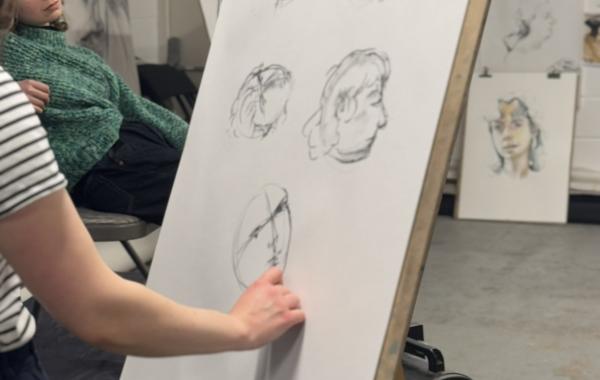 An artist stood at an easel drawing sketches of the life models face