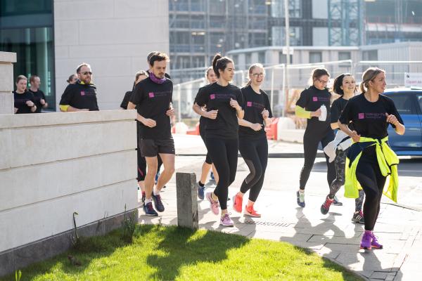 A group of runners running in the sunshine through Wellington Place