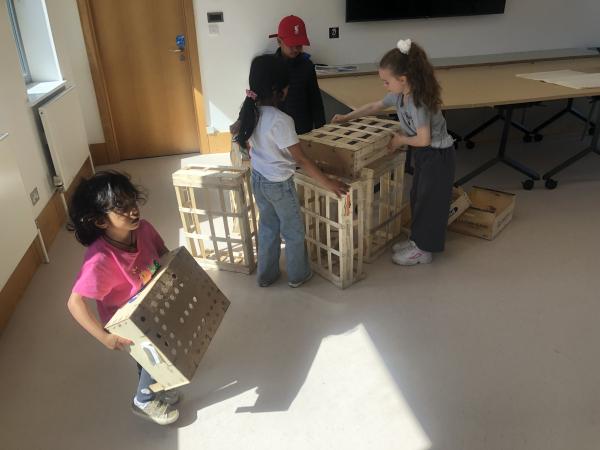 Children at a creative workshop moving and stacking wooden crates