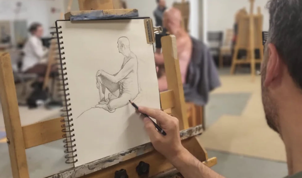 POV of an artist sat at an easel drawing a nude life model