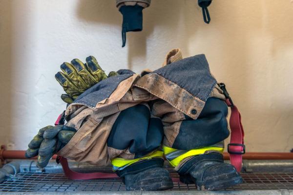 A photograph of a firefighters trousers and boots with a glove sticking out of the top. 