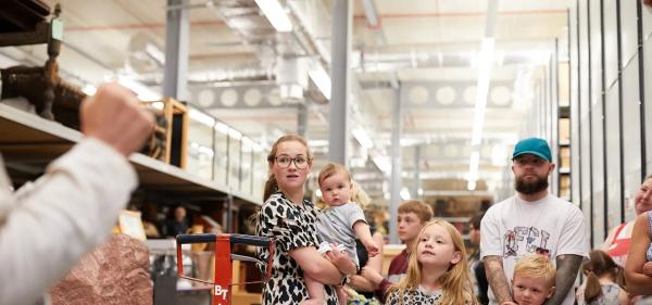 Family group standing in front of metal shelves with museum objects.