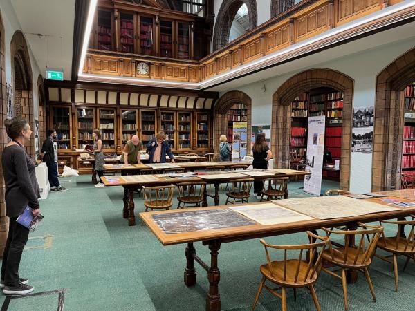 Image of interior of a library with lots of long tables filled with maps and prints.
