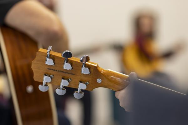 Image of room with soft focus of people playing guitar lead guitar in focus.