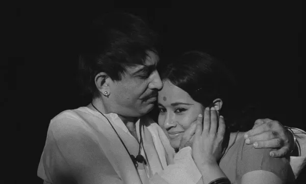 A man looks at a smiling woman with his arms around her.