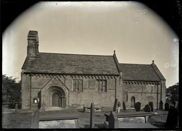 A black and white lantern slide view of a small church with Norman arched doorway (St John the Baptist, Adel, Leeds), set in a graveyard
