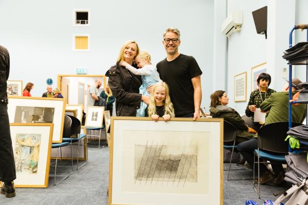 A couple and a child stood with their picture library print in Leeds Art Gallery