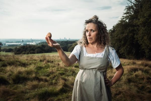 A woman in early 19th century costume holding an egg