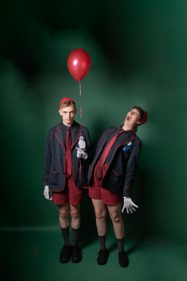 Two twins holding a red balloon