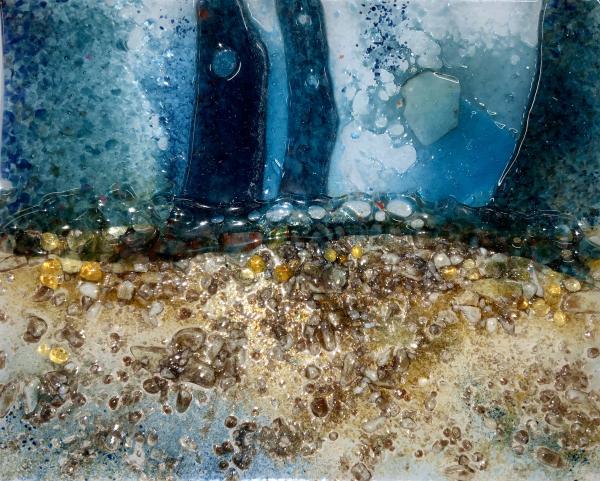 Textured glass art with tall deep blue shapes above a golden, stone-like surface.