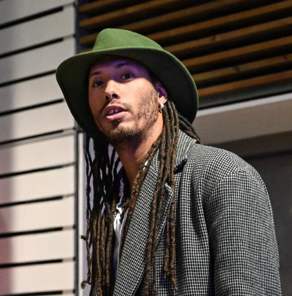 Photograph of a man with long hair wearing a hat