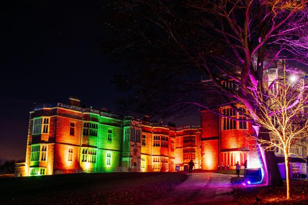 Temple Newsam House illuminated by coloured lights in the evening.