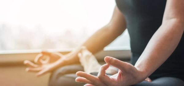 A picture of a woman sitting meditating with palms upturned.
