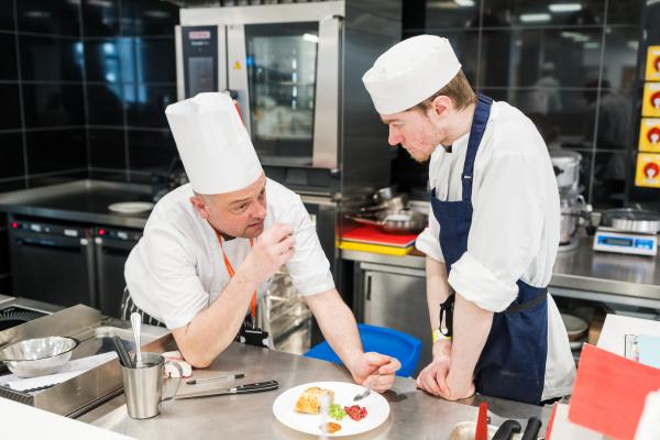 Tutor chef tasting student chefs food in a professional kitchen at Leeds City College.