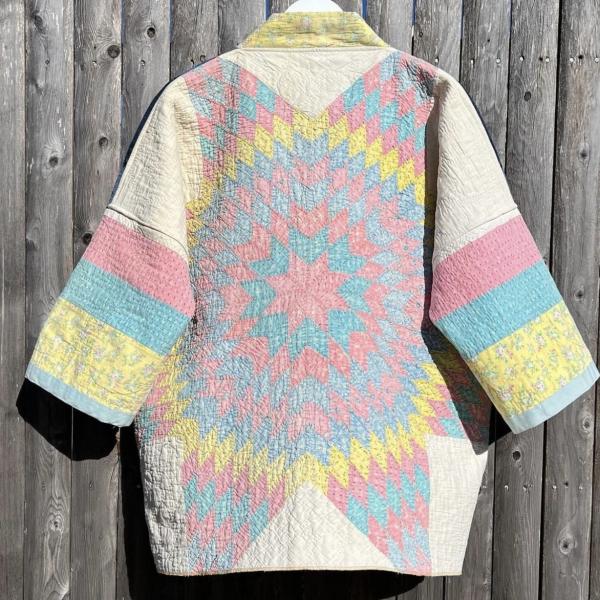 A patchwork jacket in pastel rainbow colours is hung up against a wooden background