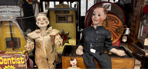 Two old clown dolls, sitting on a shelf.