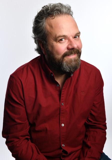 Hal Cruttenden wearing a red shirt, smiling