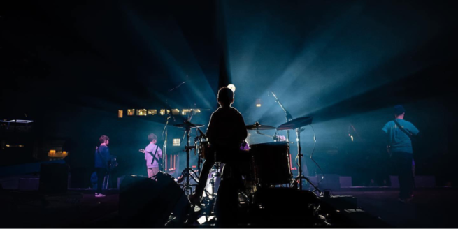 a drummer on a stage photographed from behind