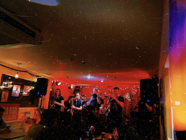 Musicians perform on a packed stage with many brass instruments.