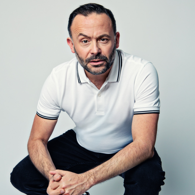 Geoff Norcott in a white shirt and black trousers. 